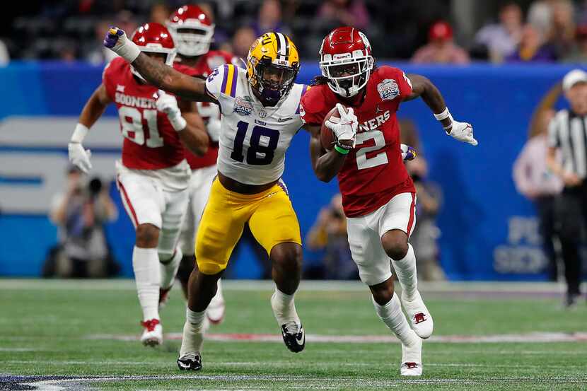 FILE - Oklahoma wide receiver CeeDee Lamb (2) gains yards as LSU's K'Lavon Chaisson (18)...