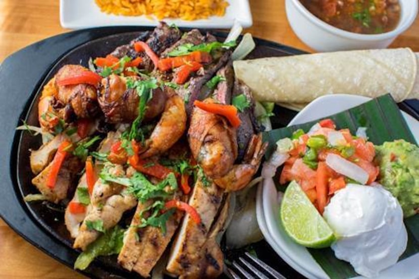 Grilled steak, chicken and bacon-wrapped shrimp fajitas are featured in the "fajitas tres,"...