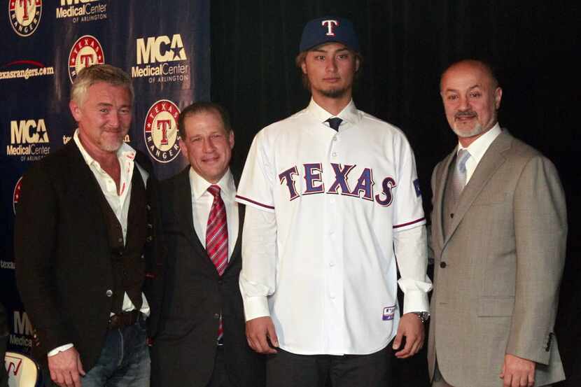 New Texas Rangers pitcher Yu Darvish poses for photos with agent Don Nomura, left, agent Arn...