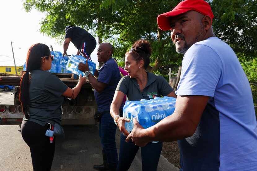 A man collects donated water bottles for drinking after Hurricane Fiona damaged water...