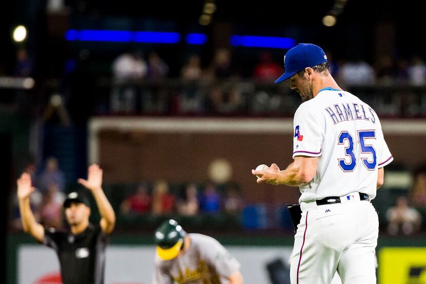 Texas Rangers starting pitcher Cole Hamels examines the ball after giving up a double to...