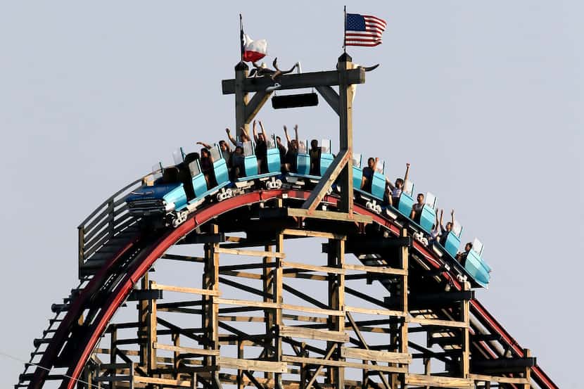 Visitors to Six Flags over Texas ride the Texas Giant as they crest the top of the tallest...