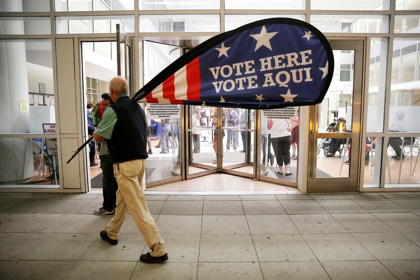 Election official Jimmy Murphy carries in a polling place sign while shutting down at the...