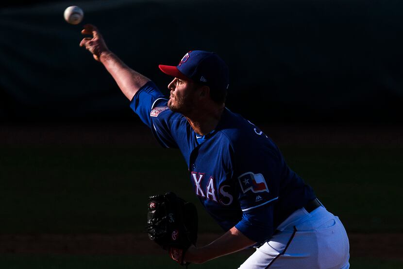 Texas Rangers pitcher Connor Sadzeck throws a pitch as the last rays of sunlight hit the...
