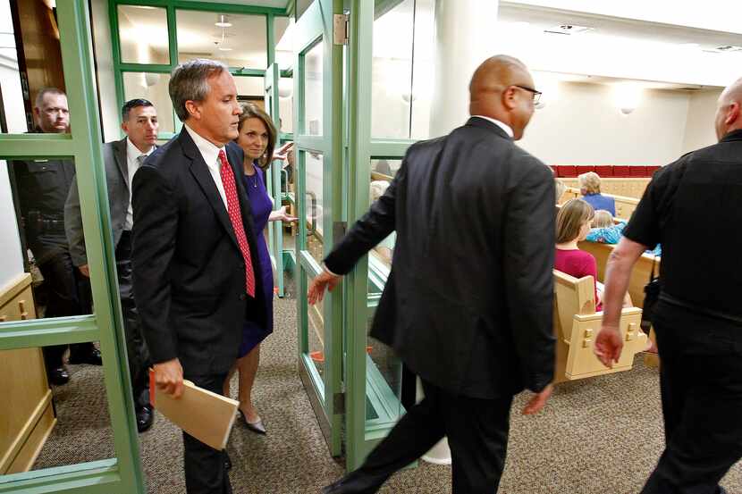With a heavy security detail, Texas Attorney General Ken Paxton (left) arrives in court...