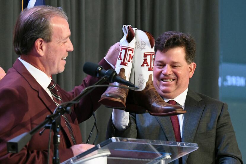 Jimbo Fisher, left, holds up a pair of Texas A&M cowboy boots next to Texas A&M athletic...