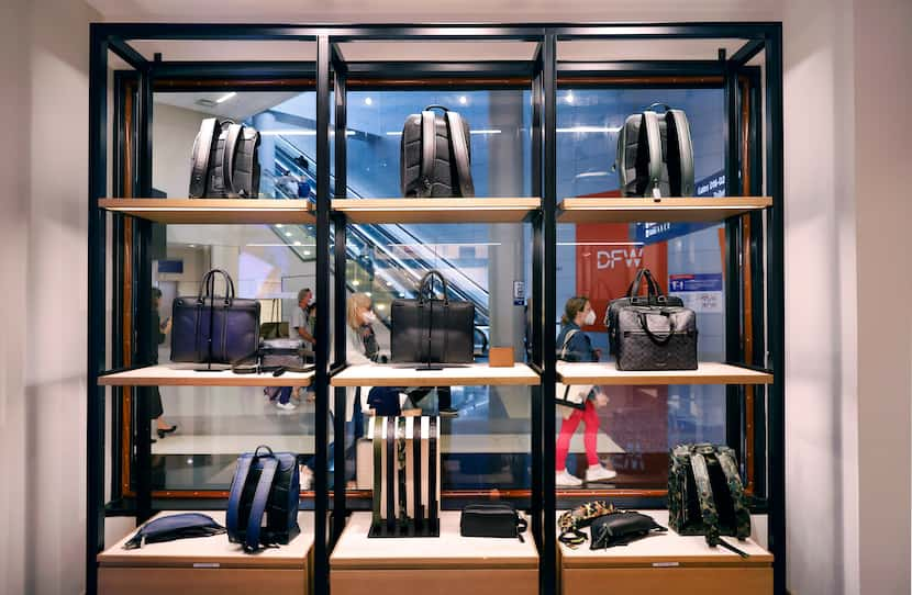 Travelers pass by a Coach store display pf handbags and backpacks in Terminal D at DFW...