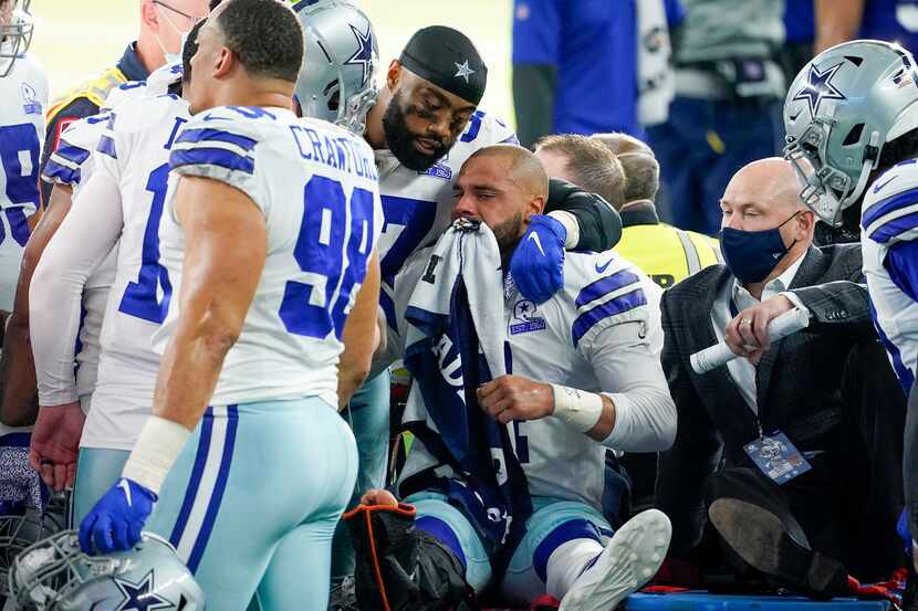 Dallas Cowboys quarterback Dak Prescott lis consoled by teammates as he leaves the field on...