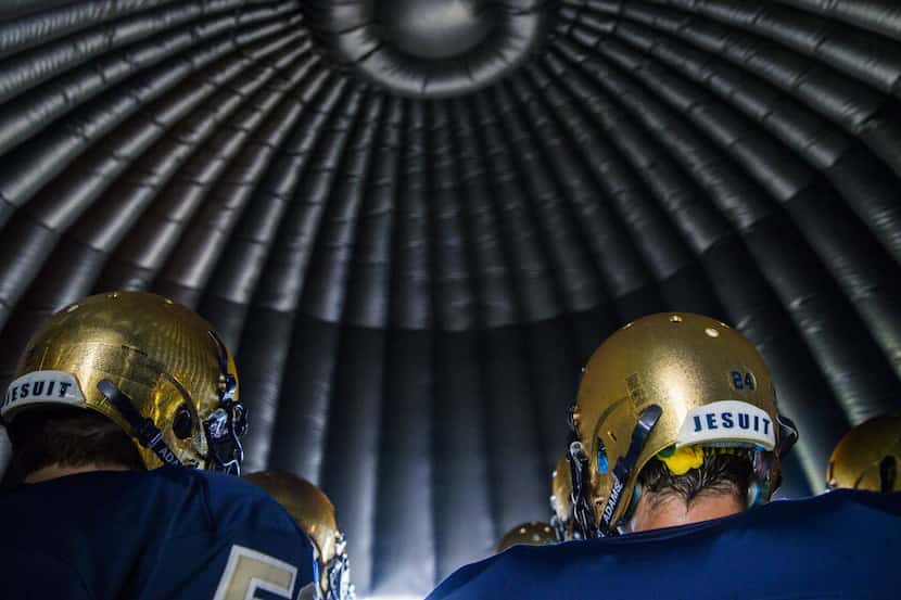 Jesuit football players wait inside an inflatable football helmet before their game against...