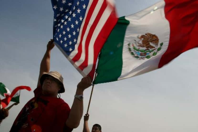 Eduardo Marquez (left) and Jaime Rosas, 14, wave the American and Mexican flag during a...