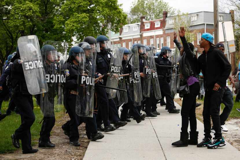 BALTIMORE, MD - APRIL 27:  A Baltimore Police officers in riot gear push protestors back...