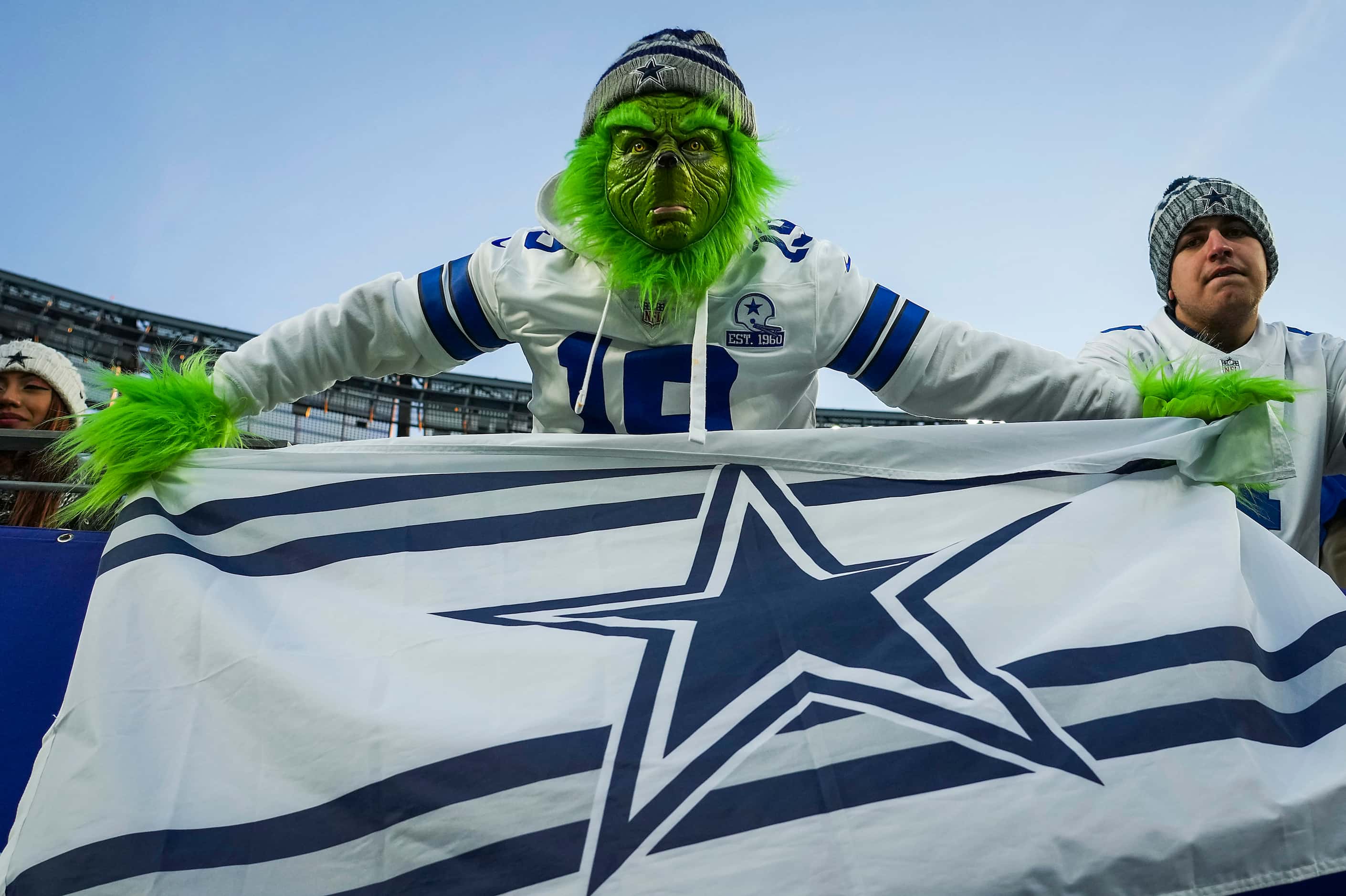 A fan wearing a Grinch costume shows of a Dallas Cowboys flag during the second half of an...