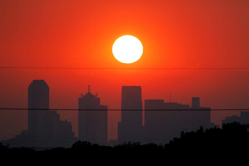 The sun sets beyond a humid city skyline following the storm that passed through Dallas.