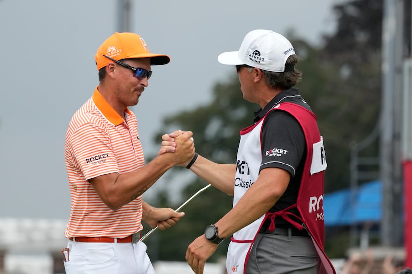 Rickie Fowler greets his caddie Ricky Romano after winning on the first play-off hole on the...