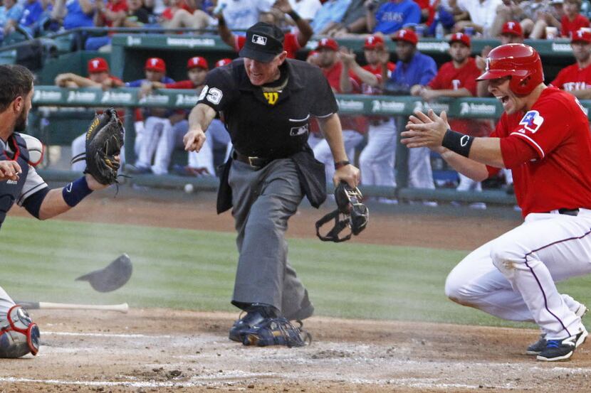 Texas catcher Chris Giminez applauds the ruling by home plate umpire Lance Barksdale, as he...