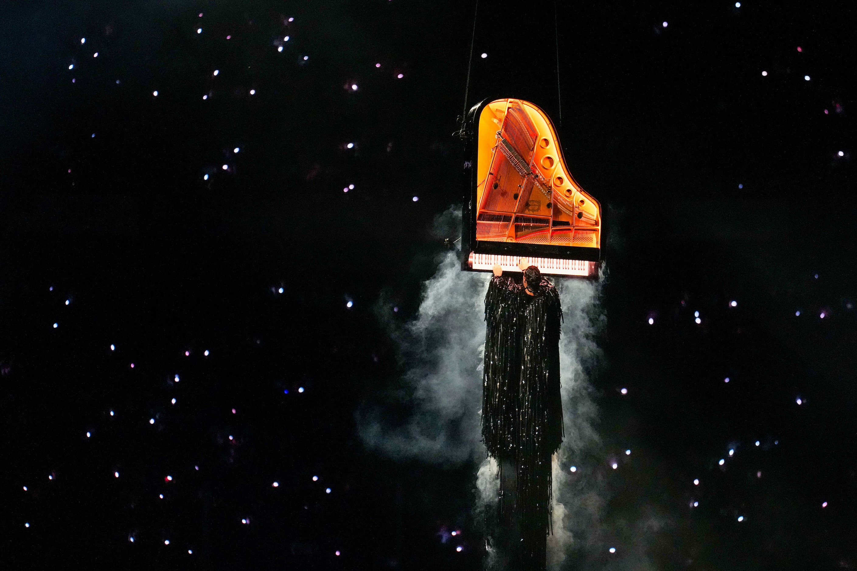 Artist Alain Roche plays a piano suspended vertically in the air during closing ceremonies...