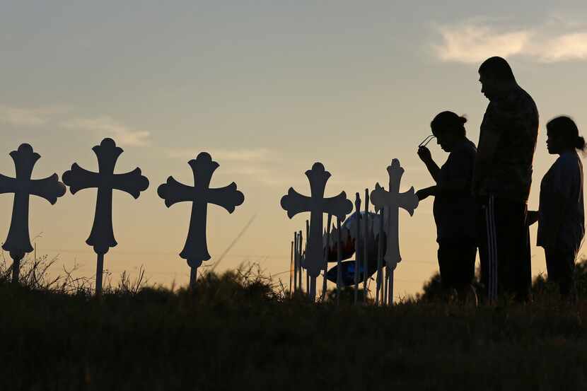 Irene and Kenneth Hernandez and their daughter Miranda Hernandez say a prayer in front of...