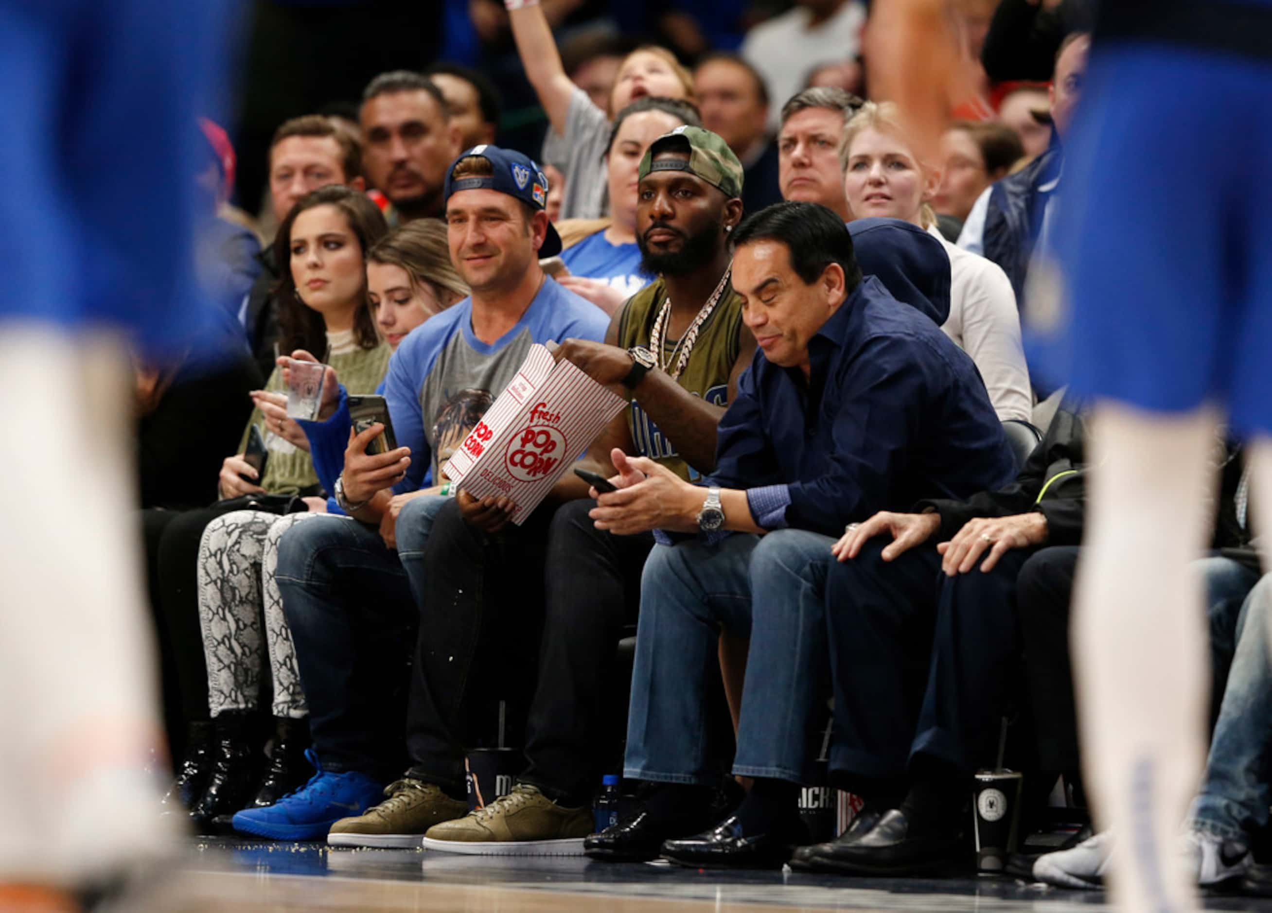 Former Dallas Cowboys player Dez Bryant eats popcorn as he watches the Dallas Mavericks play...