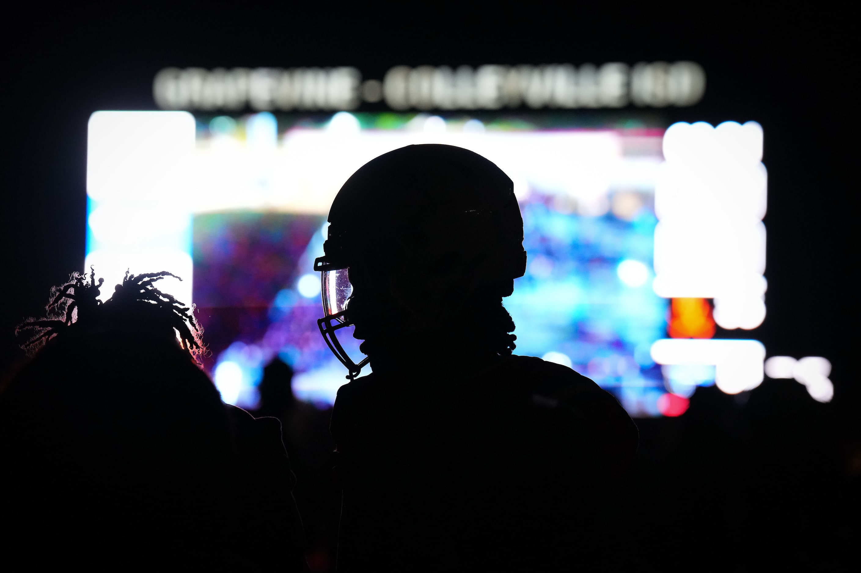 Arlington Bowie players wait on a darkened field during a delay due to the main stadium...