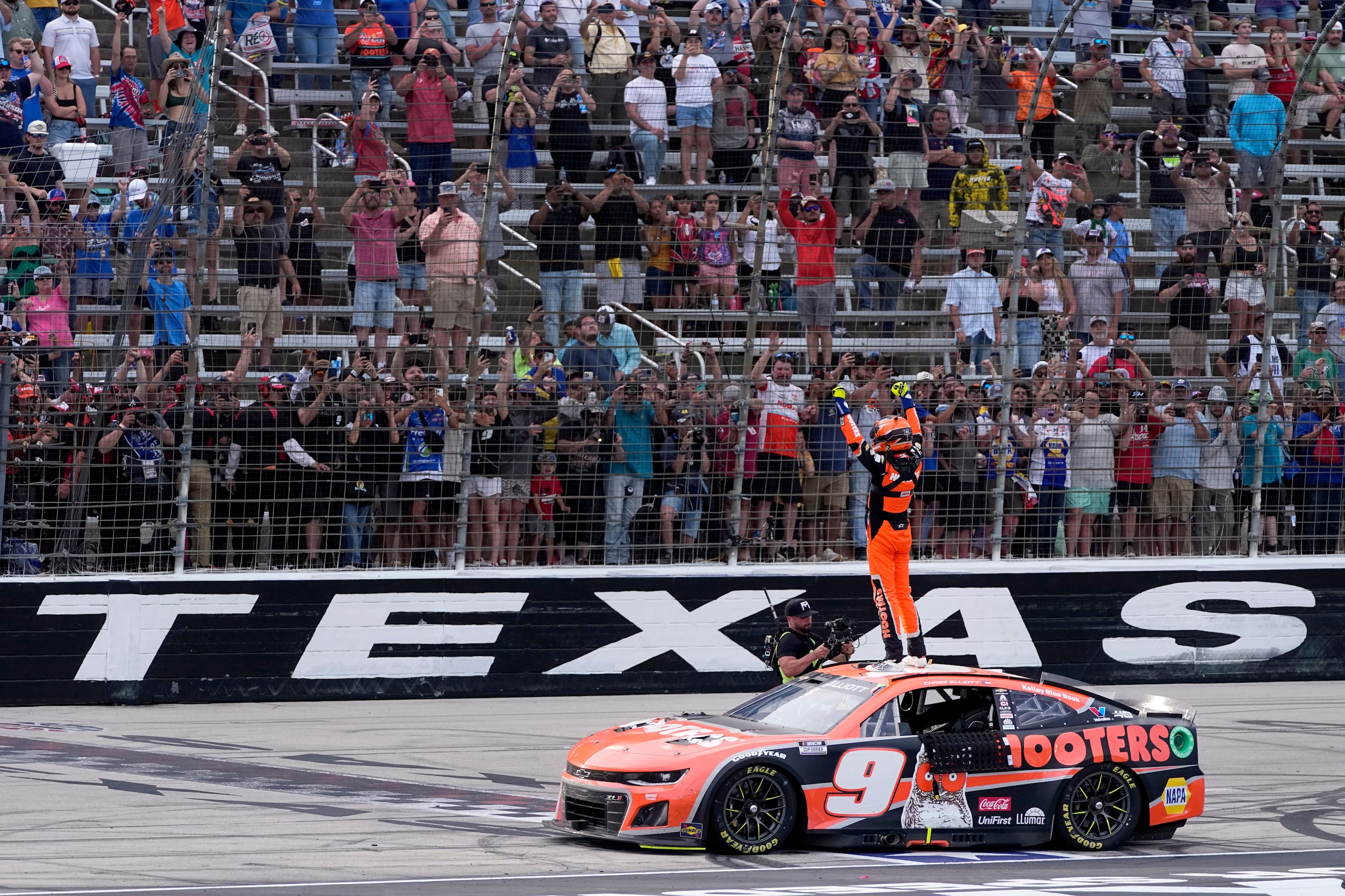 Fans cheer as Chase Elliott celebrates his win in a NASCAR Cup Series auto race at Texas...