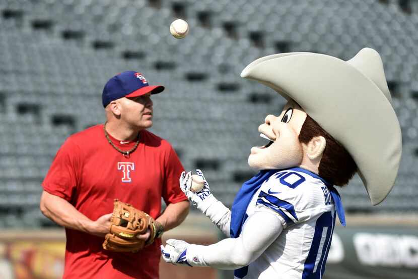 Former Texas Rangers player Kevin Mench watches as Dallas Cowboys mascot Rowdy juggles...
