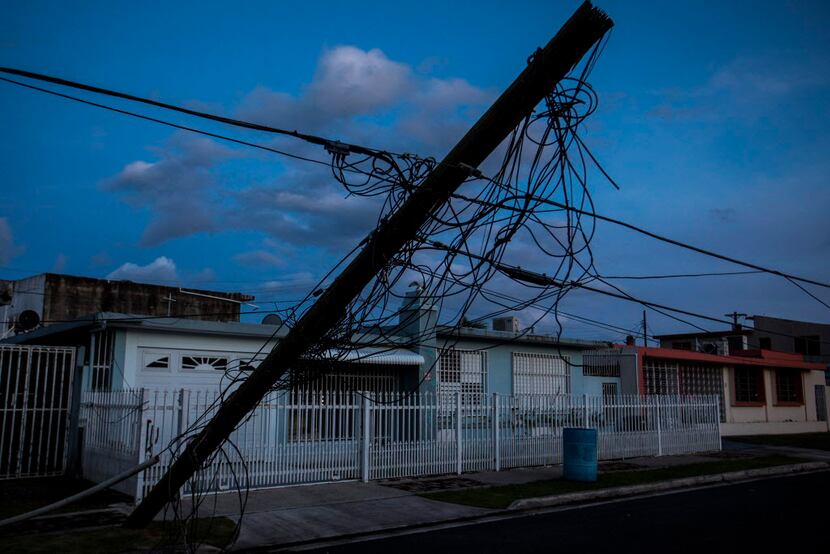Downed power lines still lean over roads in a darkened neighborhood, four months after...