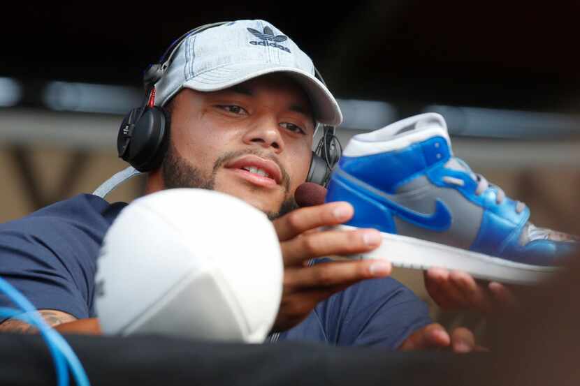 FILE - Dallas Cowboys quarterback Dak Prescott looks over a sneaker he was asked to...