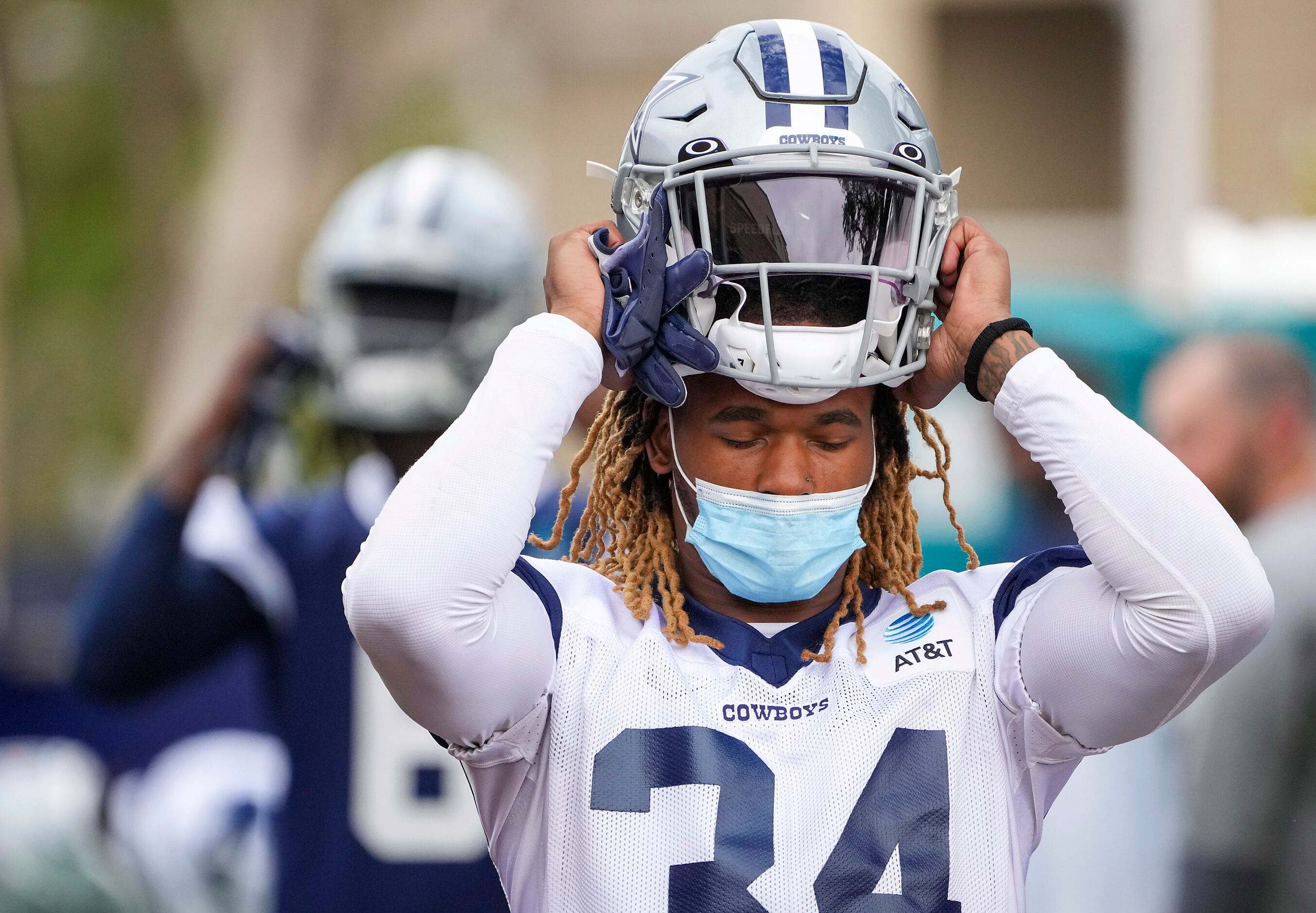 Dallas Cowboys running back Rico Dowdle (34) puts on his helmet while wearing a face mask...