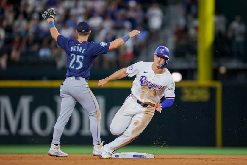 Texas Rangers' Wyatt Langford, right, rounds second base past Seattle Mariners shortstop...