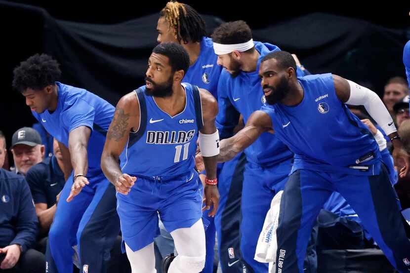 Dallas Mavericks guard Kyrie Irving (11) is congratulated by teammates on the bench after...