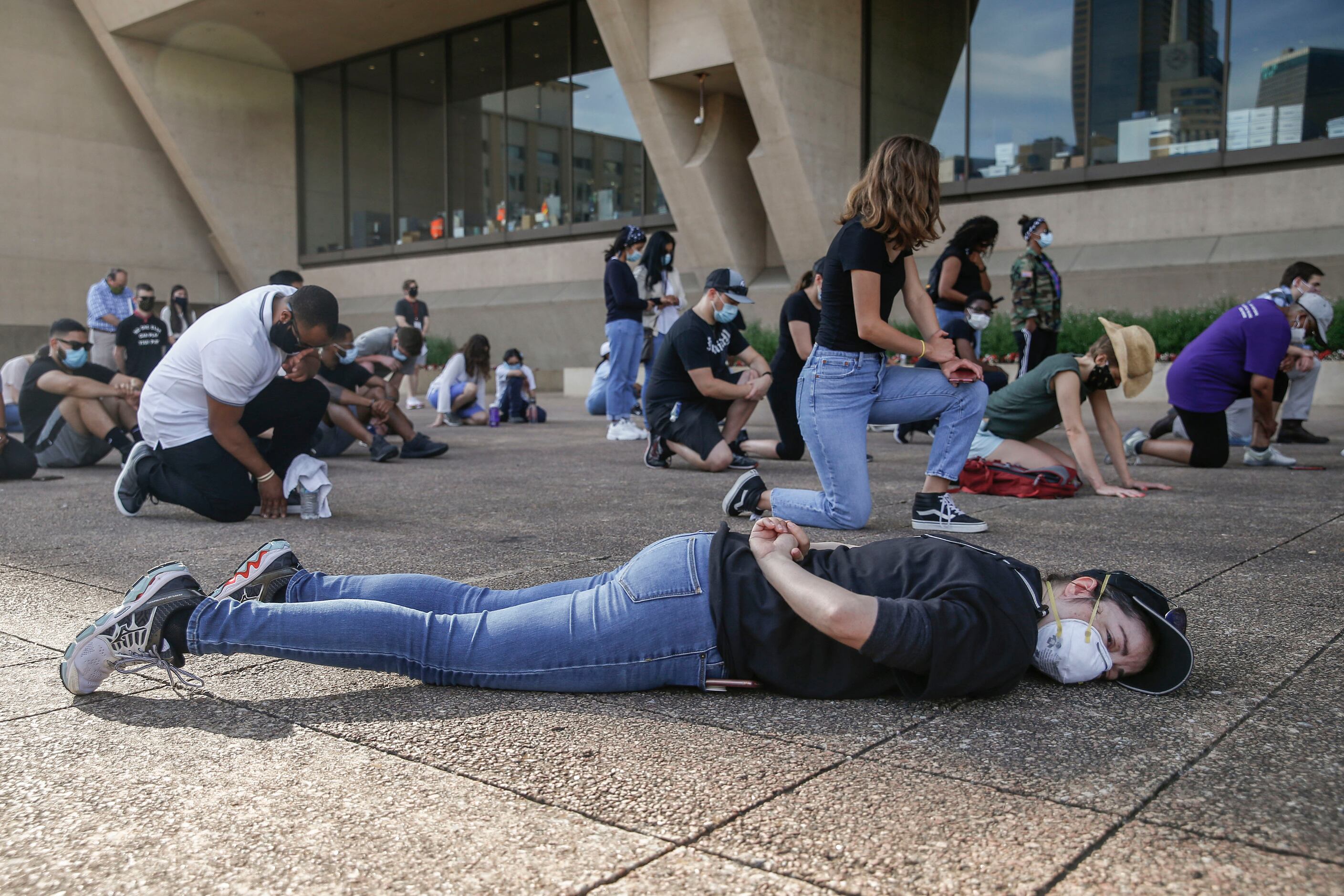 Community members kneel and lay on the ground for an 8 minute and 46 second a moment of...