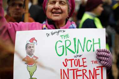 Diane Tepfer holds a sign with an image of Federal Communications Commission Chairman Ajit...