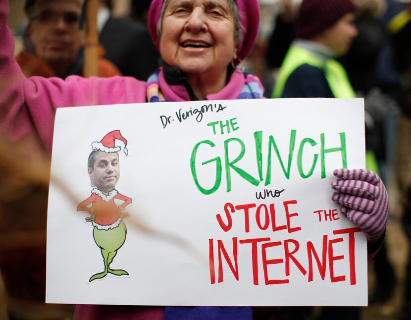 Diane Tepfer holds a sign with an image of Federal Communications Commission Chairman Ajit...