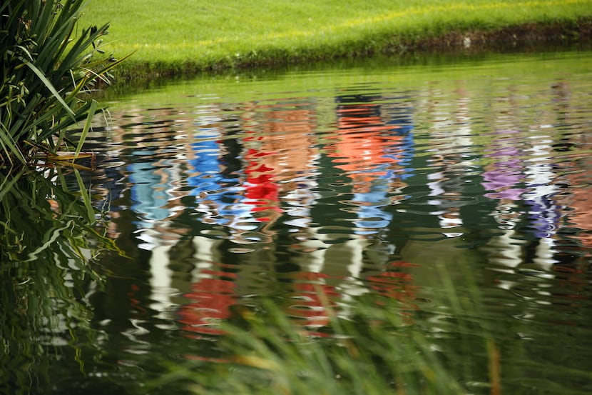 Golf spectators are reflected in the pond fronting the No. 9 green during the Dean and...