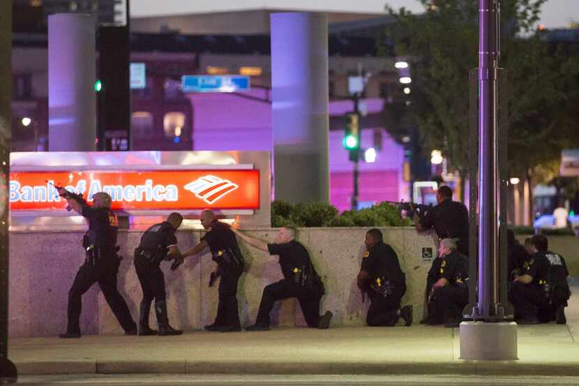 Dallas Police take up position along a wall at the corner of Lamar at Main as they train...