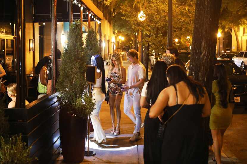 Guests wait to have their identification checked outside of Parliament Bar in Dallas on July...