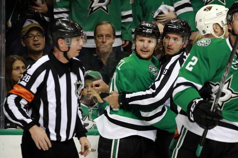 Dallas Stars left wing Antoine Roussel (21) is restrained by referee Dan O'Rourke (9) after...