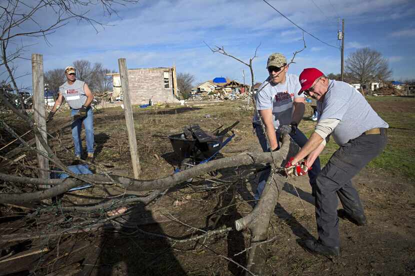 George McCoy (far right) and Joe Curry work together to clear downed tree limbs in Glenn...