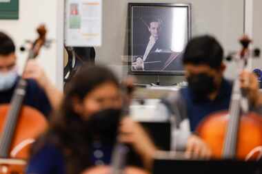 A portrait of maestro Eduardo Mata overlooks as eight graders take part in an orchestra...