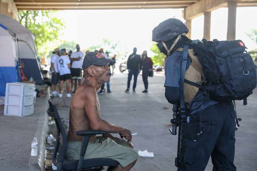 Gary Mitchell (left) speaks with a member of the Elm Fork John Brown Gun Club at a homeless...