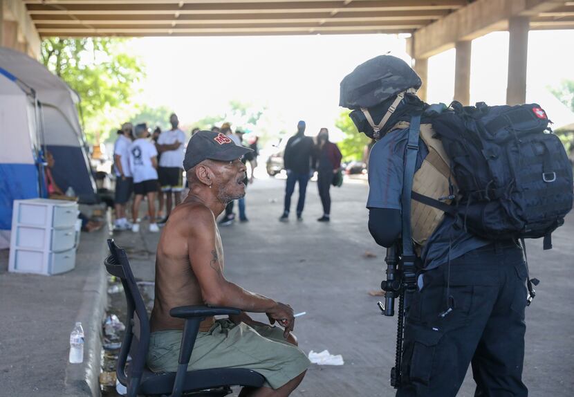 Gary Mitchell (left) speaks with a member of the Elm Fork John Brown Gun Club at a homeless...