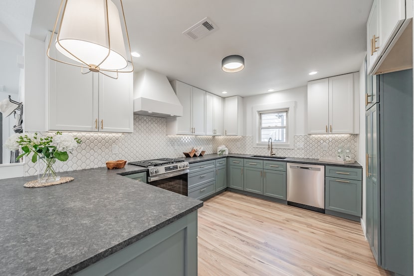 The updated kitchen has blue-gray cabinetry below the countertop and white cabinetry above....