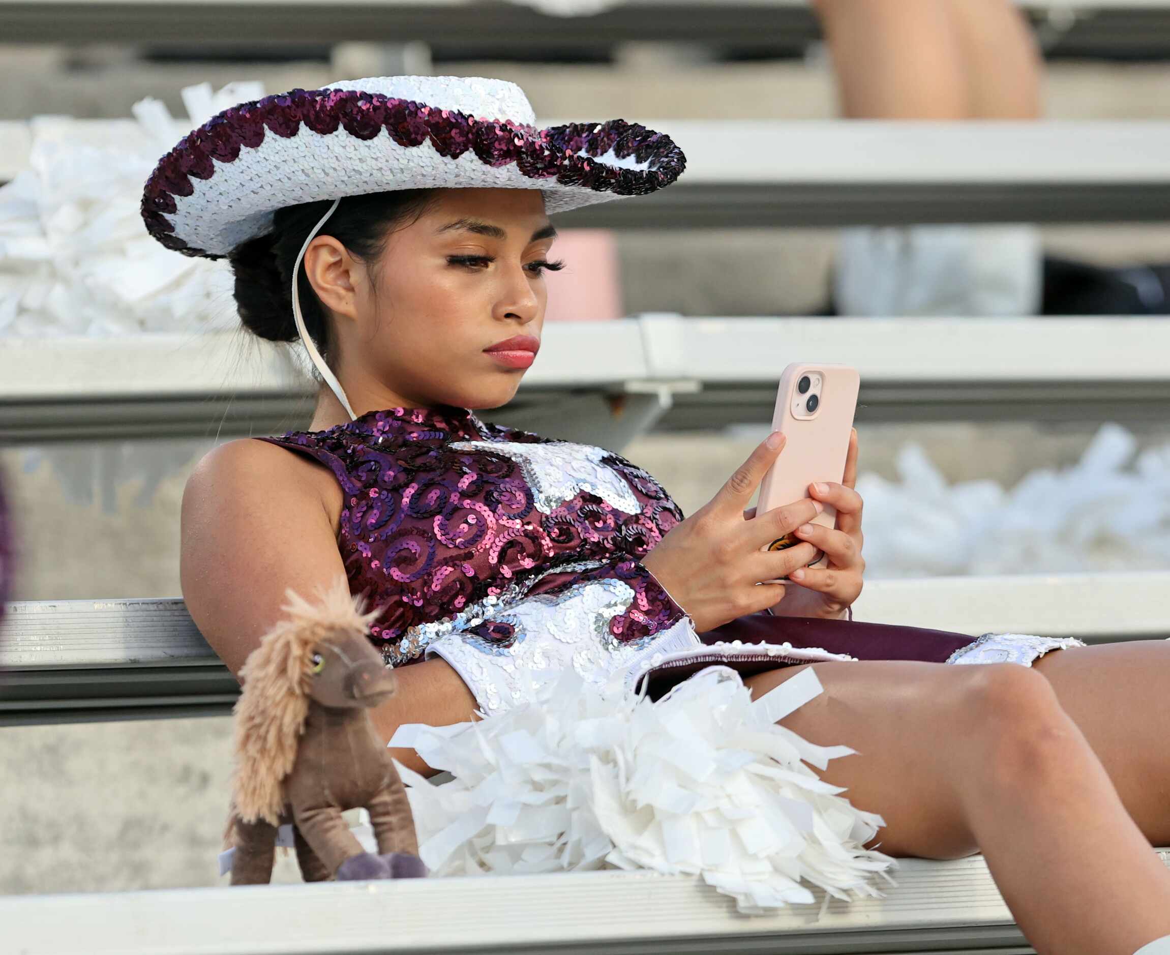 A Mesquite High drill team member, next to her small stuffed horse, checks her messages...