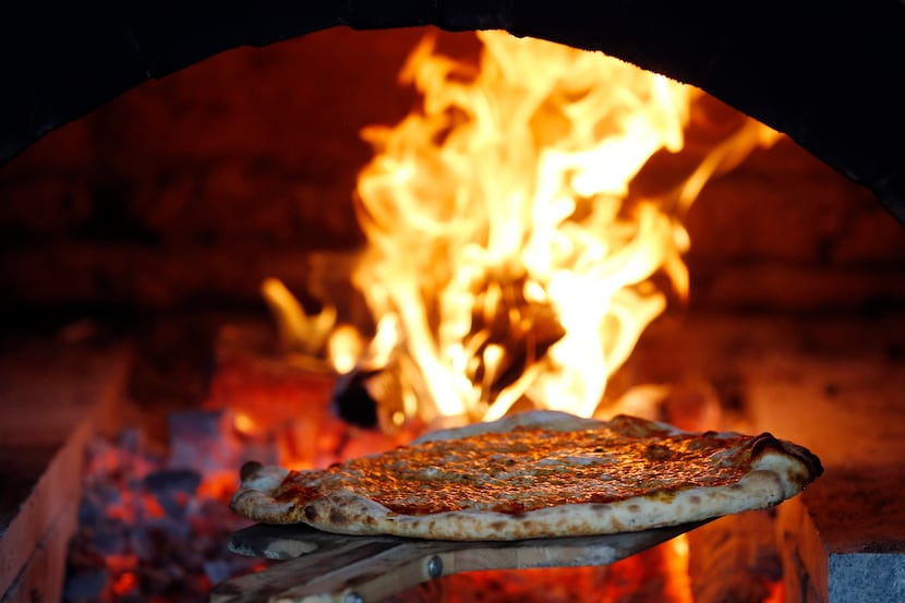 Cheese pizza is pulled from the wood fired oven at Flatbread Company in Dallas. The...