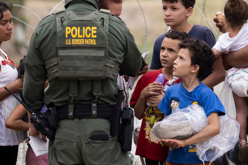 (From right) Brothers Oliver, 8, Kevin, 10, and Hugo, 13, look up at a Border Patrol agent...