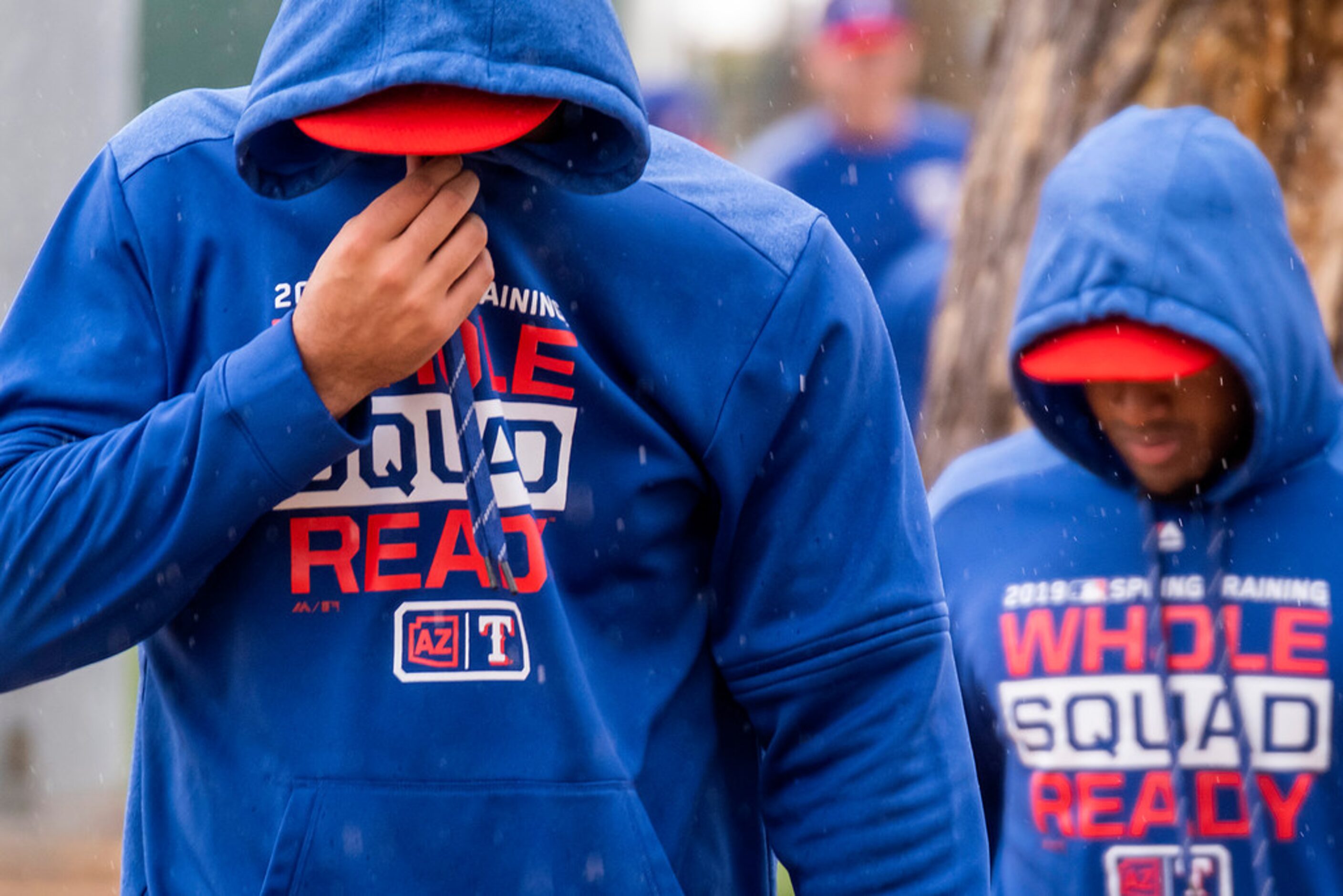 Texas Rangers infielder Ronald Guzman bundles up against a cold rain while walking between...