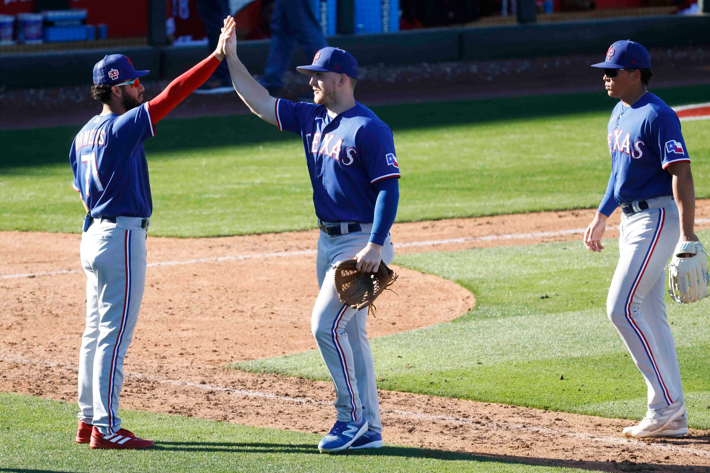 Texas Rangers infielder Jonathan Ornelas, (left) high-fives outfielder Joe McCarthy (center)...