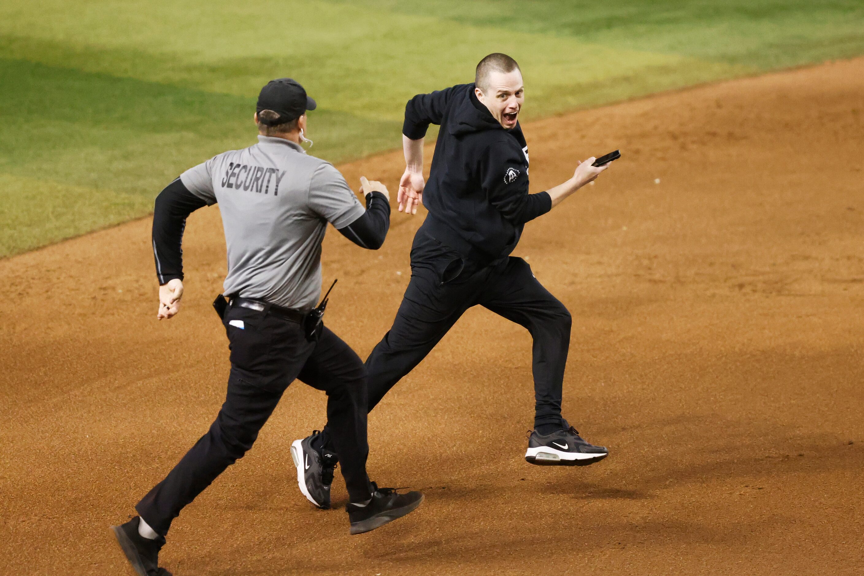 Security chases after a fan who ran onto the field during Game 4 of the World Series between...