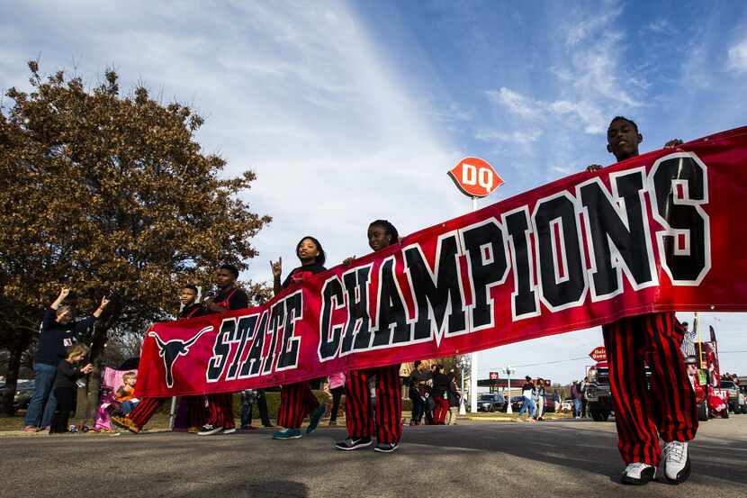 Students carry a state champions banner during a parade honoring the back-to-back state...