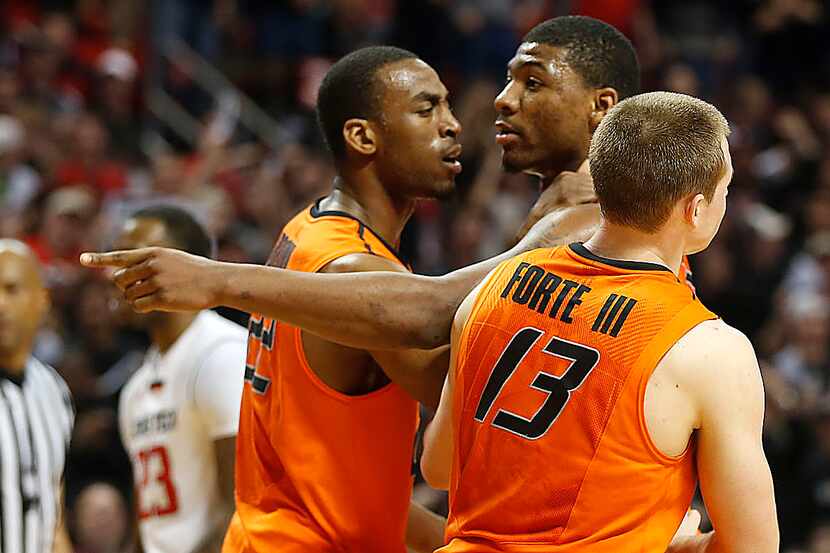 Oklahoma State's Markel Brown(22) and Phil Forte (13) hold Marcus Smart (33) after Smart...